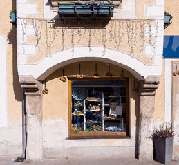 selective focus on an ancient wall with a window decorated with traditional pretzels. Autumn morning in a small town