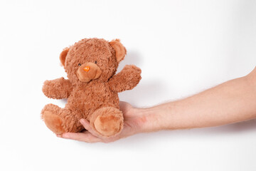 male hand holding a toy bear on a white