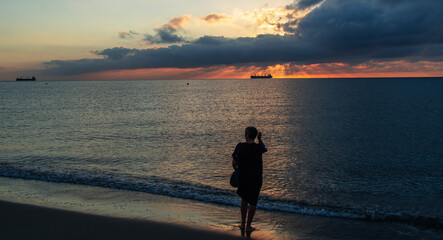 Woman walking on sea shore to see a sunrise.