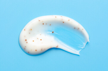 A sample of a cosmetic skin scrub with jojoba oil. Blue background