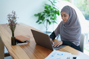 eautiful Muslim woman using computer and documents working in office