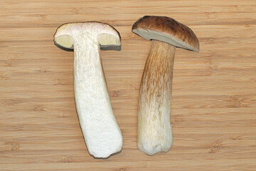 Two halves of an edible mushroom cep (Boletus edulis) lying on a cutting board. Cross-section...