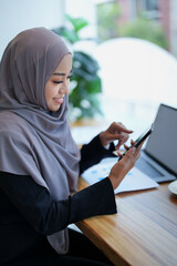 Beautiful Muslim woman shopping online using her phone and credit card