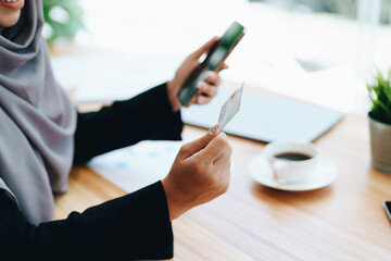 Beautiful Muslim woman shopping online using her phone and credit card