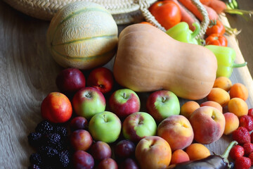 Round straw bag and various healthy fruits and vegetables on wooden background. Selective focus.
