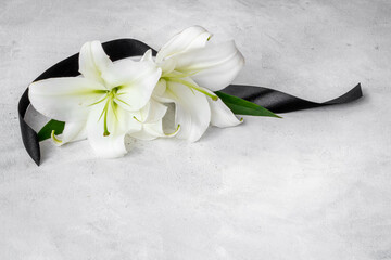 Flowers heads of white lilies with black ribbon. Mourning or funeral background