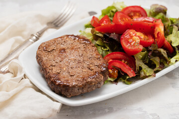 three fried ground meat with fresh salad on white plate