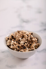 Burnt popcorn in the small white bowl on ceramic