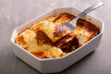 Fresh lasagna with meat and tomato sauce baked in the oven in a ceramic dish.