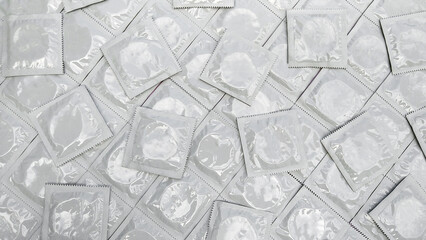 Many white packages of unopened condoms as a background.