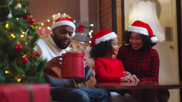 christmas Holiday Celebration family Concept.Portrait of happy black parents giving present to excited adolescent daughter,happy girl opens gift box with Christmas and New year sitting on floor