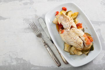 Fried fish with baked vegetables on white dish