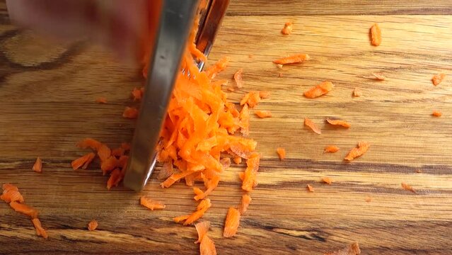 The cook rubs carrots on a grater. Work of the cook.