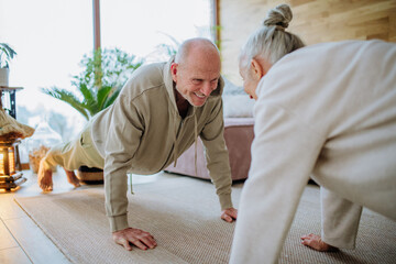 Senior couple exercising together in their living room during cold autumn day.