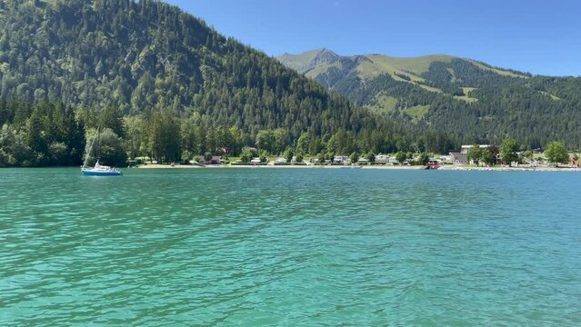 a sailing boat is sailing on the Achen Lake near the coastline at Achenkirch during a sunny summer day - K4 video 