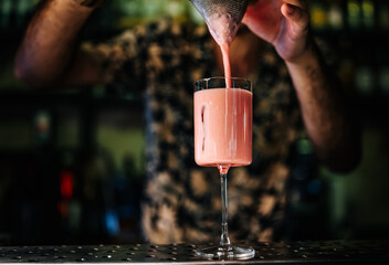 man hand bartender making pink cocktail in glass on the bar counter