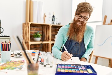 Fototapeta premium Young redhead man smiling confident drawing on notebook at art studio