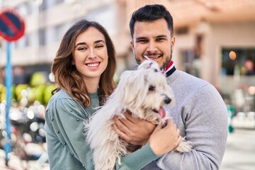 Man and woman holding dog standing together at street