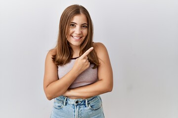 Young brunette woman standing over isolated background cheerful with a smile of face pointing with hand and finger up to the side with happy and natural expression on face