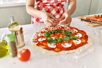 Obraz na płótnie Canvas Young beautiful hispanic woman preparing italian pizza at the kitchen
