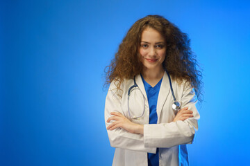 Studio shot of a young female doctor looking at camera against a blue background.