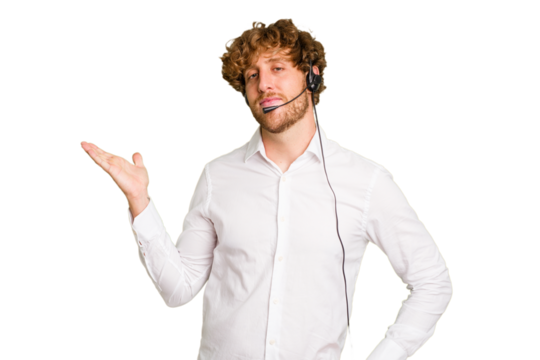 Telemarketer man working with a headset isolated on green chroma background showing a copy space on a palm and holding another hand on waist.