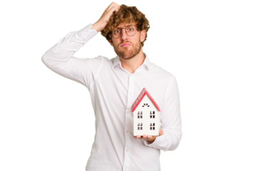 Business caucasian man holding toy house isolated on white background being shocked, she has remembered important meeting.