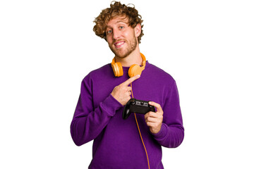 Young caucasian gamer man holding a game controller isolated on white background smiling and pointing aside, showing something at blank space. © Asier