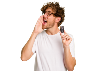 Young caucasian man holding car keys isolated on white background shouting and holding palm near opened mouth.