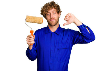 Young painter man holding a roll isolated on white background showing a dislike gesture, thumbs...