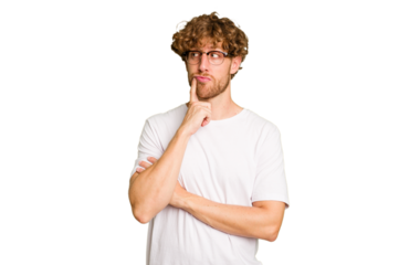 Young caucasian man isolated on green chroma background contemplating, planning a strategy, thinking about the way of a business.