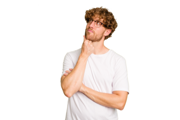 Young caucasian man isolated on green chroma background thinking and looking up, being reflective, contemplating, having a fantasy.