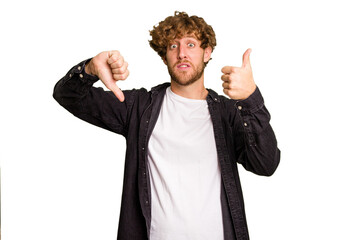 Young caucasian man isolated on green chroma background showing thumbs up and thumbs down,...
