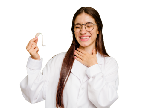 Young otorhinolaryngologist caucasian woman holding hearing aid isolated laughs out loudly keeping hand on chest. - Powered by Adobe