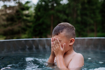 Little boy in outdoor hot tub. Summer holiday, vacation concept.