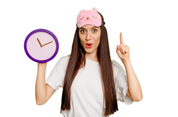 Young caucasian woman wearing pajama and holding a clock having some great idea, concept of creativity.