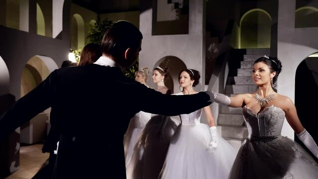 professional dancers are dancing in ballroom, beautiful ladies in white and elegant men in black