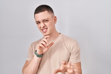 Young man standing over isolated background disgusted expression, displeased and fearful doing...