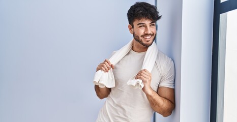 Young hispanic man smiling confident wearing towel at sport center