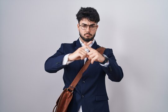 Hispanic man with beard wearing business clothes rejection expression crossing fingers doing negative sign