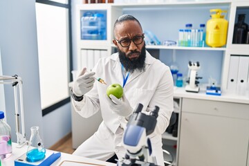 African american man working at scientist laboratory with apple skeptic and nervous, frowning upset because of problem. negative person.