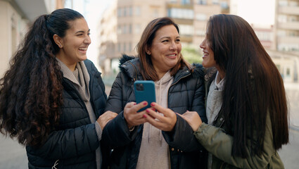 Mother and daugthers using smartphone standing together at street