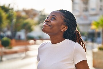 African american woman smiling confident looking to the sky at street