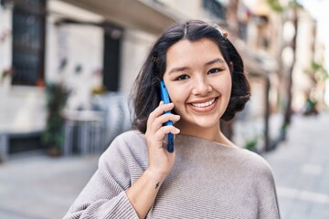 Young woman smiling confident talking on the smartphone at street