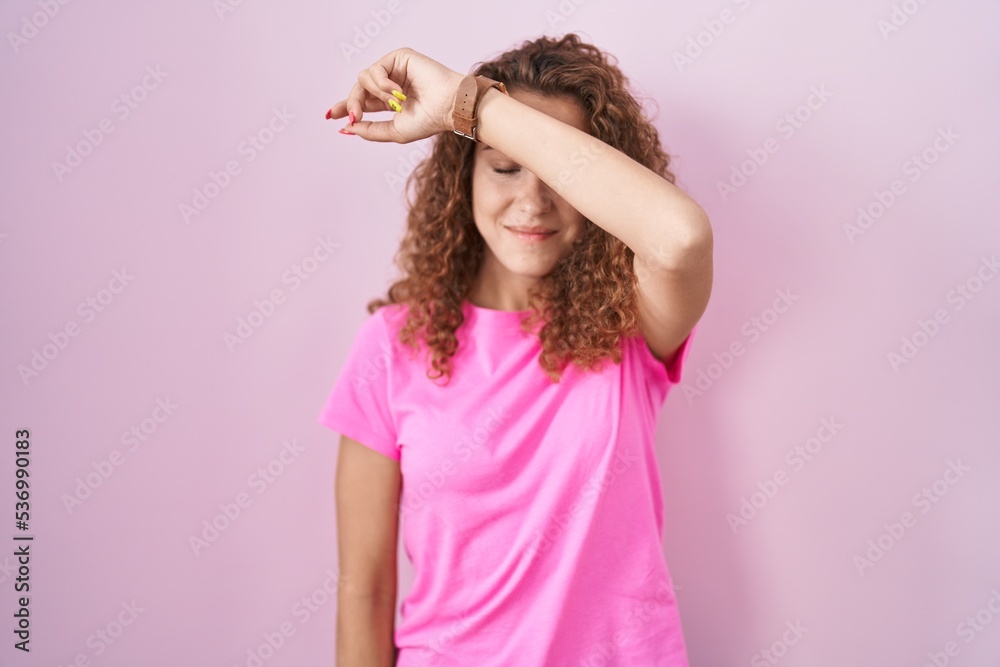 Sticker young caucasian woman standing over pink background covering eyes with arm, looking serious and sad.