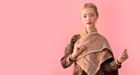 Portrait of a Thai woman wearing Thai traditional dress with pink background, as a guideline for presenting Thailand tourism business.