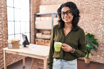 Young latin woman ecommerce business worker drinking coffee at office - obrazy, fototapety, plakaty