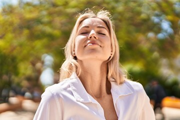 Young blonde woman smiling confident breathing at park - obrazy, fototapety, plakaty