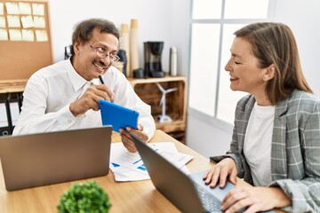 Middle age man and woman business workers using touchpad working at office
