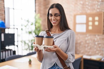 Young beautiful hispanic woman business worker smiling confident holding take away coffee at office